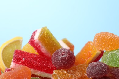 Pile of delicious bright jelly candies on light blue background, closeup