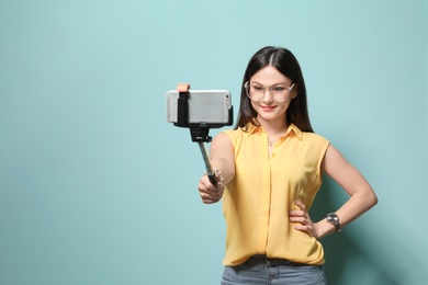 Photo of Attractive young woman taking selfie on color background