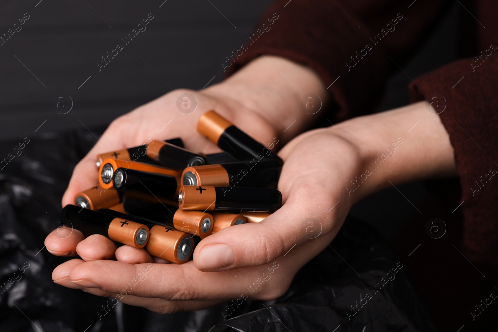 Image of Woman holding many used electric batteries in her hands, closeup