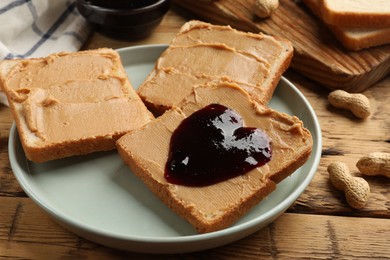 Photo of Tasty peanut butter sandwiches with jam on wooden table, closeup