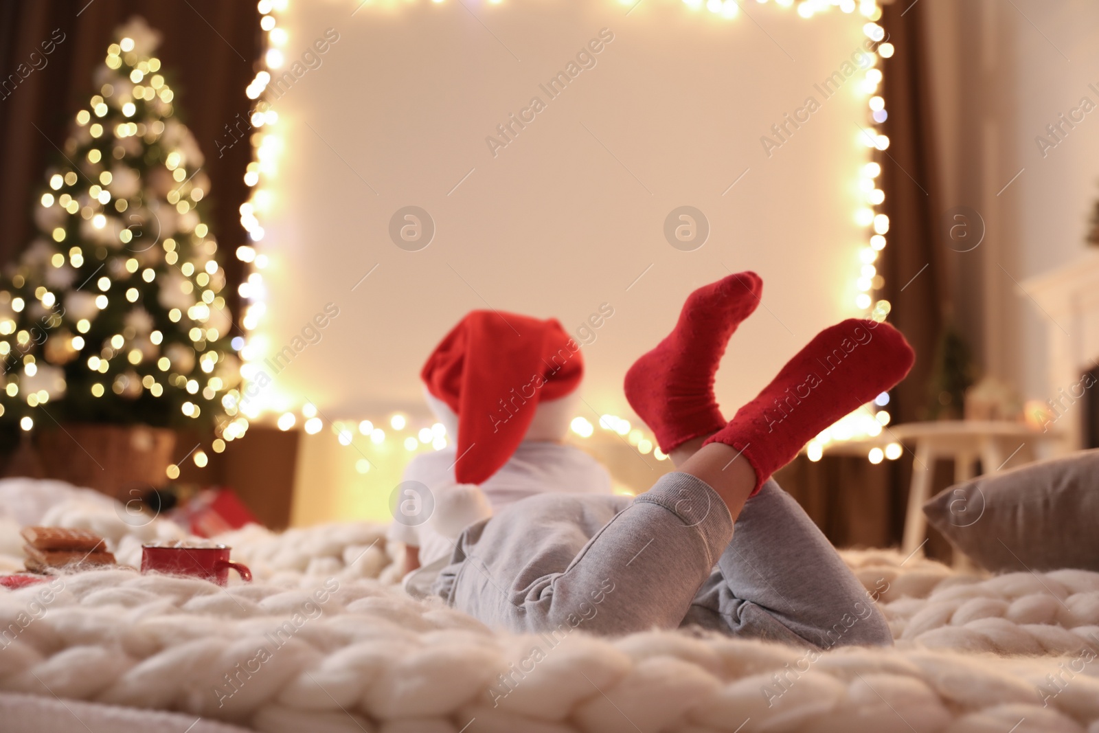 Photo of Child watching movie using video projector at home. Cozy Christmas atmosphere