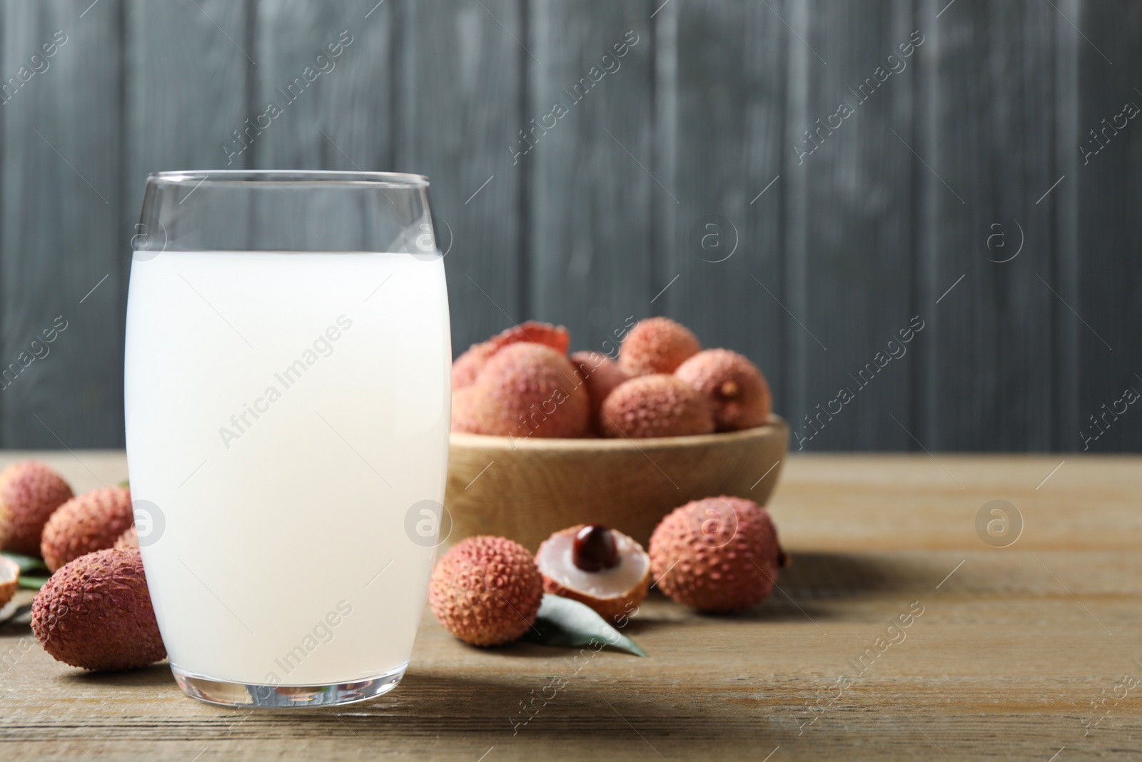 Photo of Lychee juice and fresh fruits on wooden table. Space for text