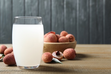 Photo of Lychee juice and fresh fruits on wooden table. Space for text