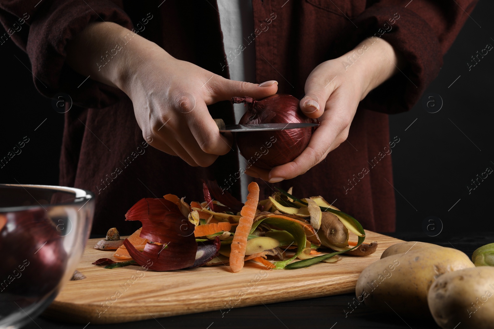 Photo of Woman peeling fresh onion with knife at table, closeup