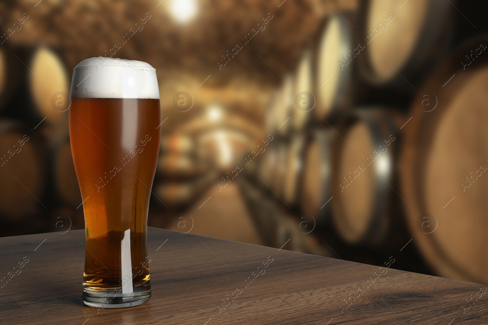 Image of Glass with fresh beer on wooden table in cellar, space for text