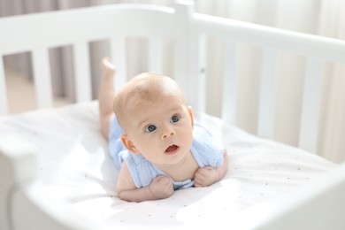 Photo of Cute little baby lying in crib at home