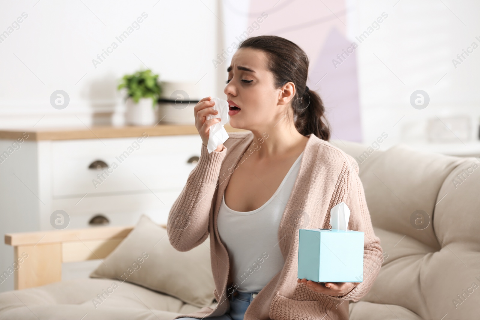 Photo of Young woman suffering from runny nose in living room