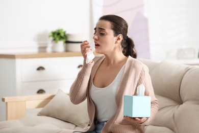 Young woman suffering from runny nose in living room