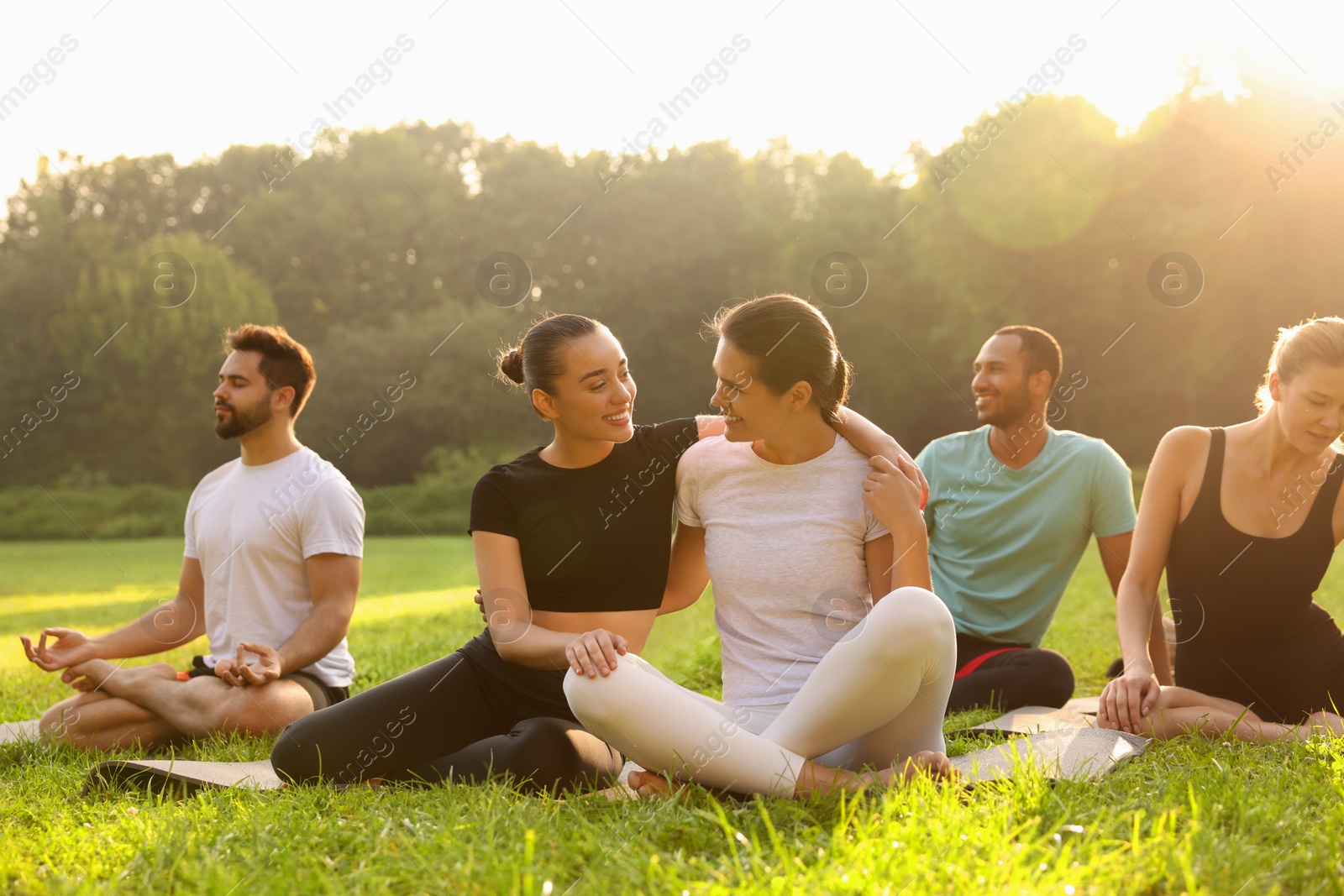 Photo of Women spending time together while practicing yoga on mats outdoors