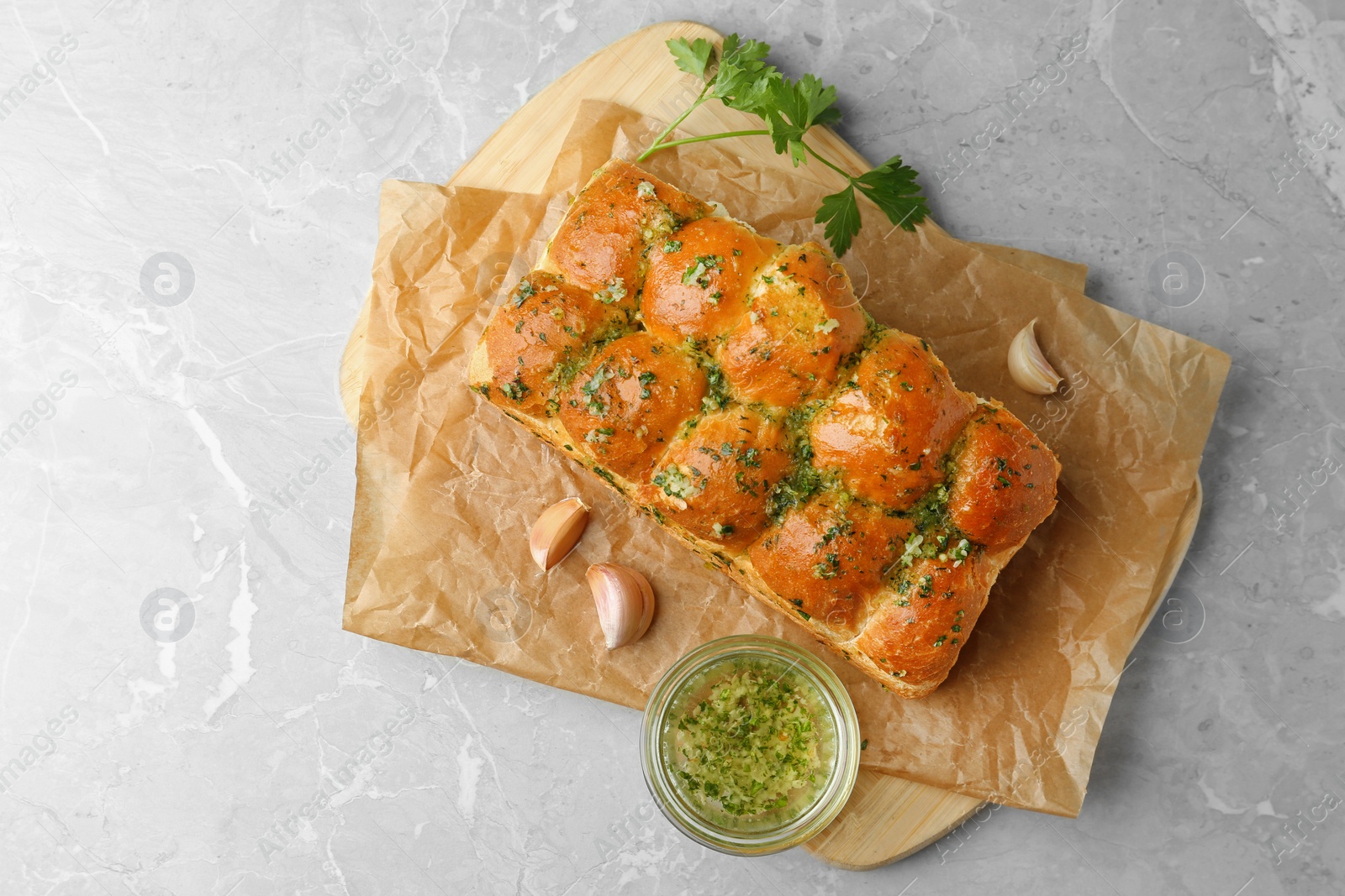 Photo of Buns of bread with garlic and herbs on grey table, flat lay