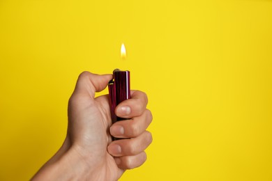 Photo of Woman holding lighter on yellow background, closeup. Space for text