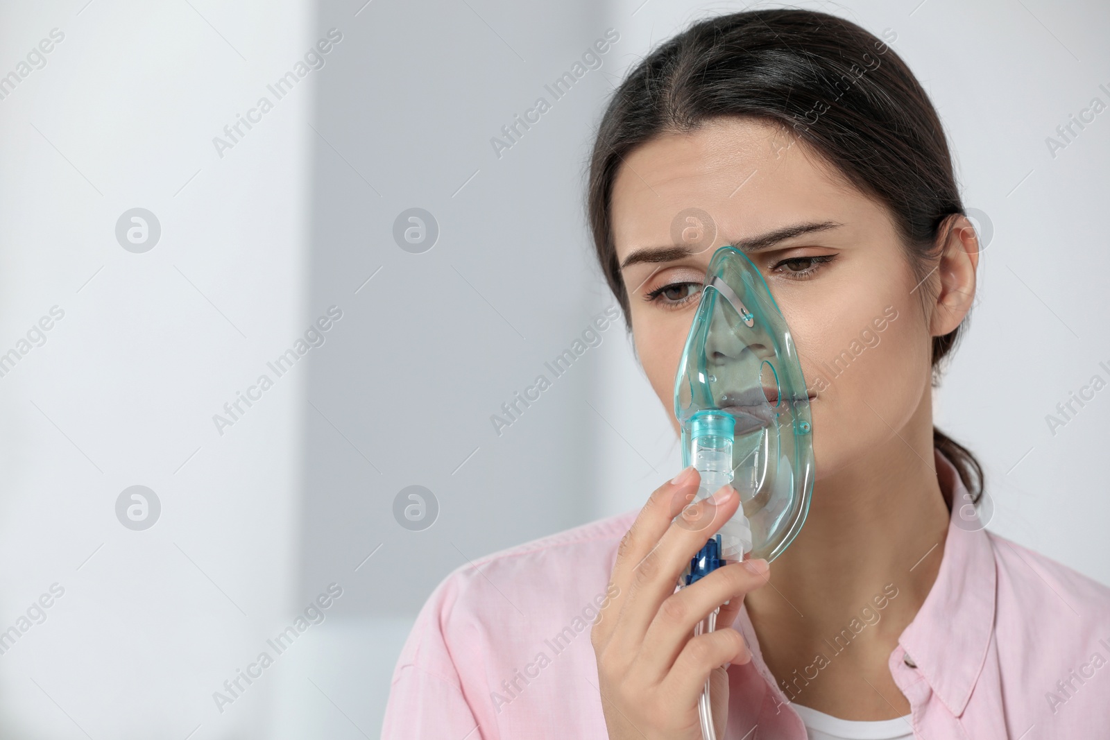 Photo of Sick young woman using nebulizer at home, space for text