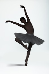 Beautiful ballerina dancing on white background. Dark silhouette of dancer