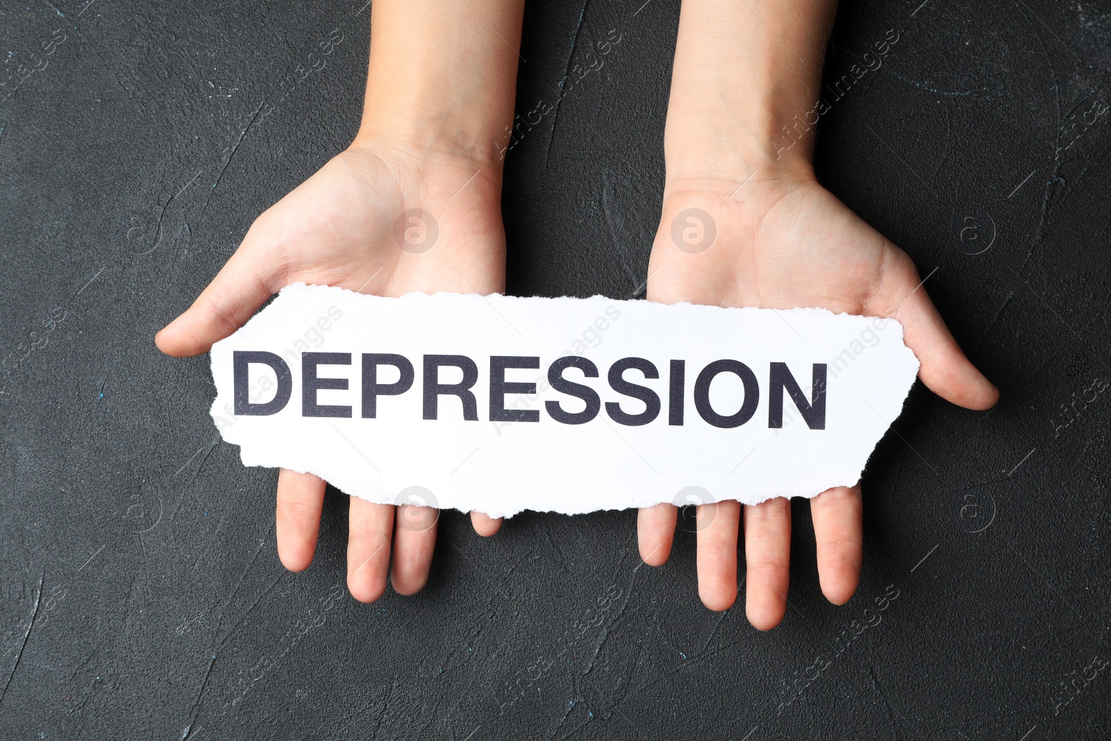 Photo of Woman holding torn away paper with word Depression on dark background, top view