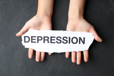 Woman holding torn away paper with word Depression on dark background, top view