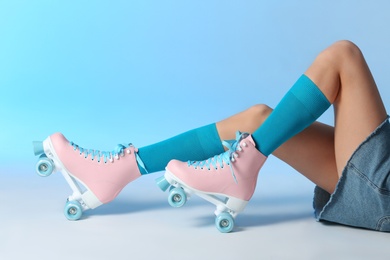 Photo of Woman with vintage roller skates on color background, closeup