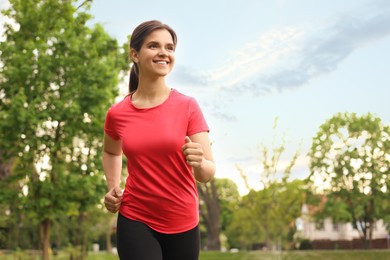 Young woman jogging around park in morning. Space for text