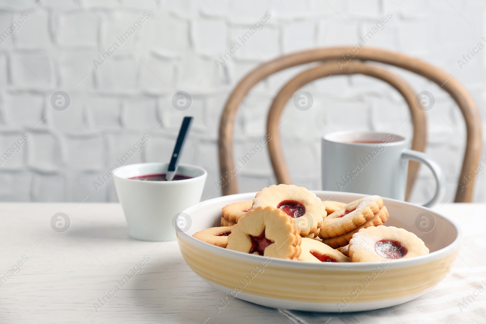 Photo of Traditional Christmas Linzer cookies with sweet jam and cup of tea on table