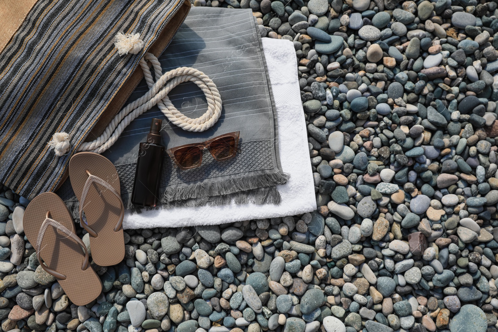 Photo of Stylish bag, flip flops and spray on stones outdoors, flat lay. Space for text