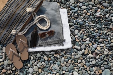 Stylish bag, flip flops and spray on stones outdoors, flat lay. Space for text