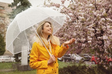 Image of Young woman with umbrella in park on rainy day