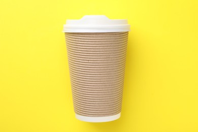 Photo of One paper cup on yellow background, top view. Coffee to go