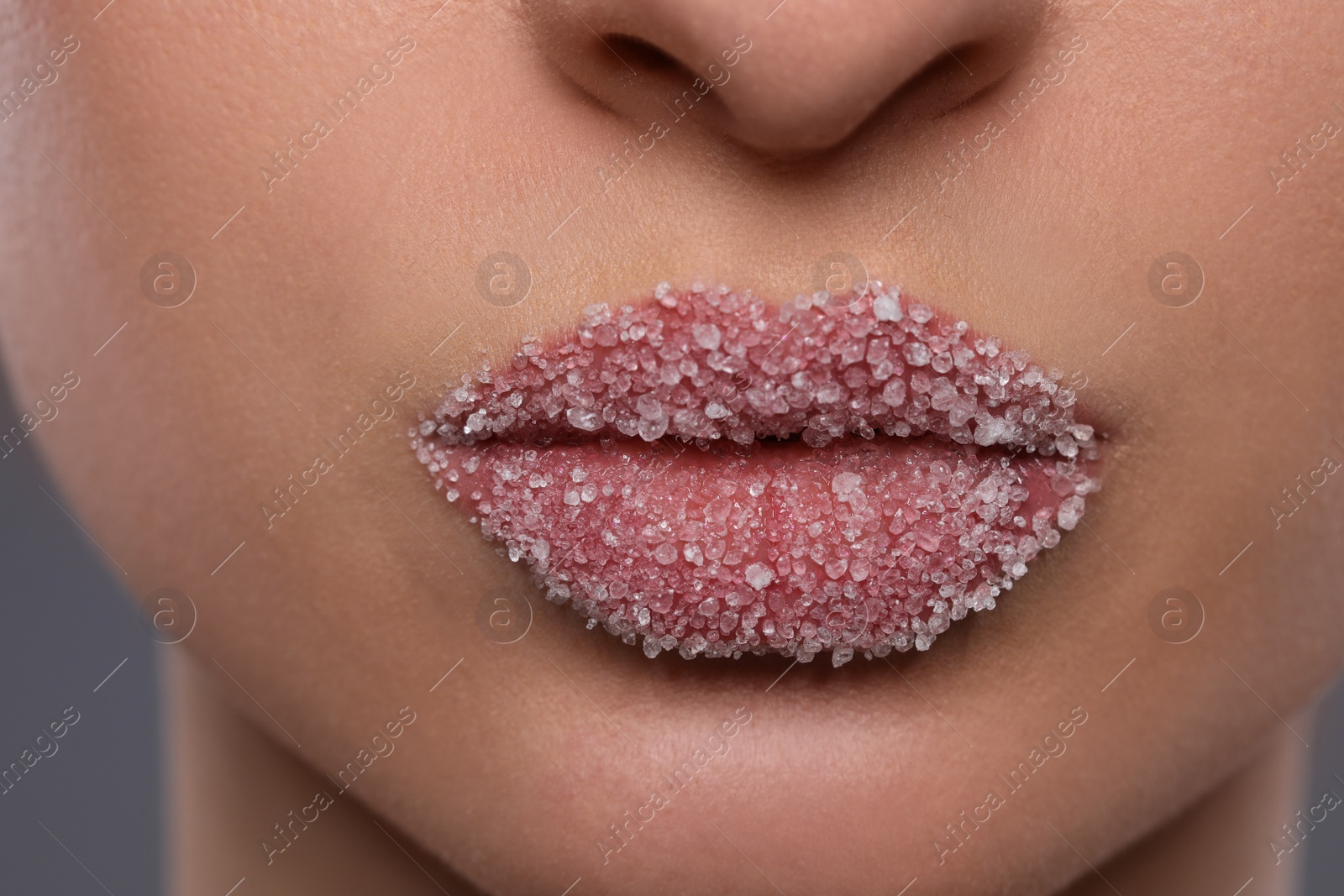 Photo of Woman with beautiful lips covered in sugar on grey background, closeup