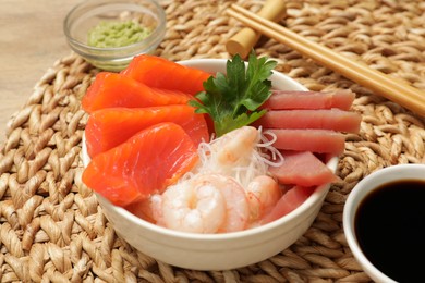 Photo of Delicious sashimi set of salmon, shrimps and tuna served with funchosa, parsley, wasabi and soy sauce on table, closeup