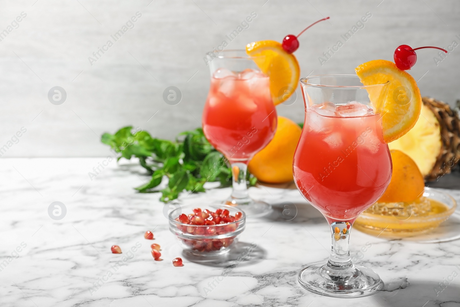 Photo of Glasses of delicious cocktail with ice on white marble table. Space for text