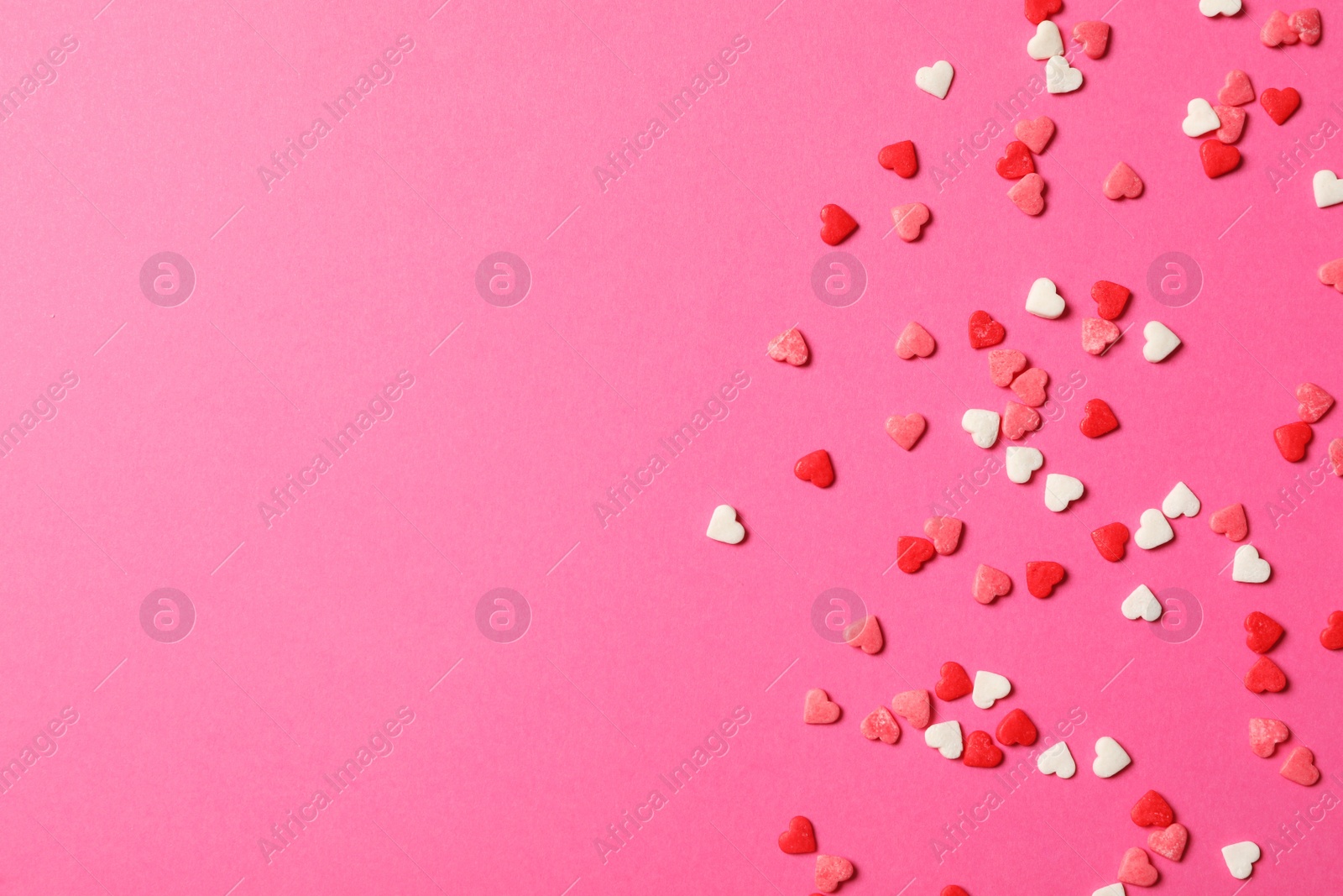 Photo of Heart shaped sprinkles on pink background, flat lay. Space for text