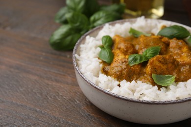 Photo of Delicious rice and chicken with curry sauce served on wooden table, closeup. Space for text