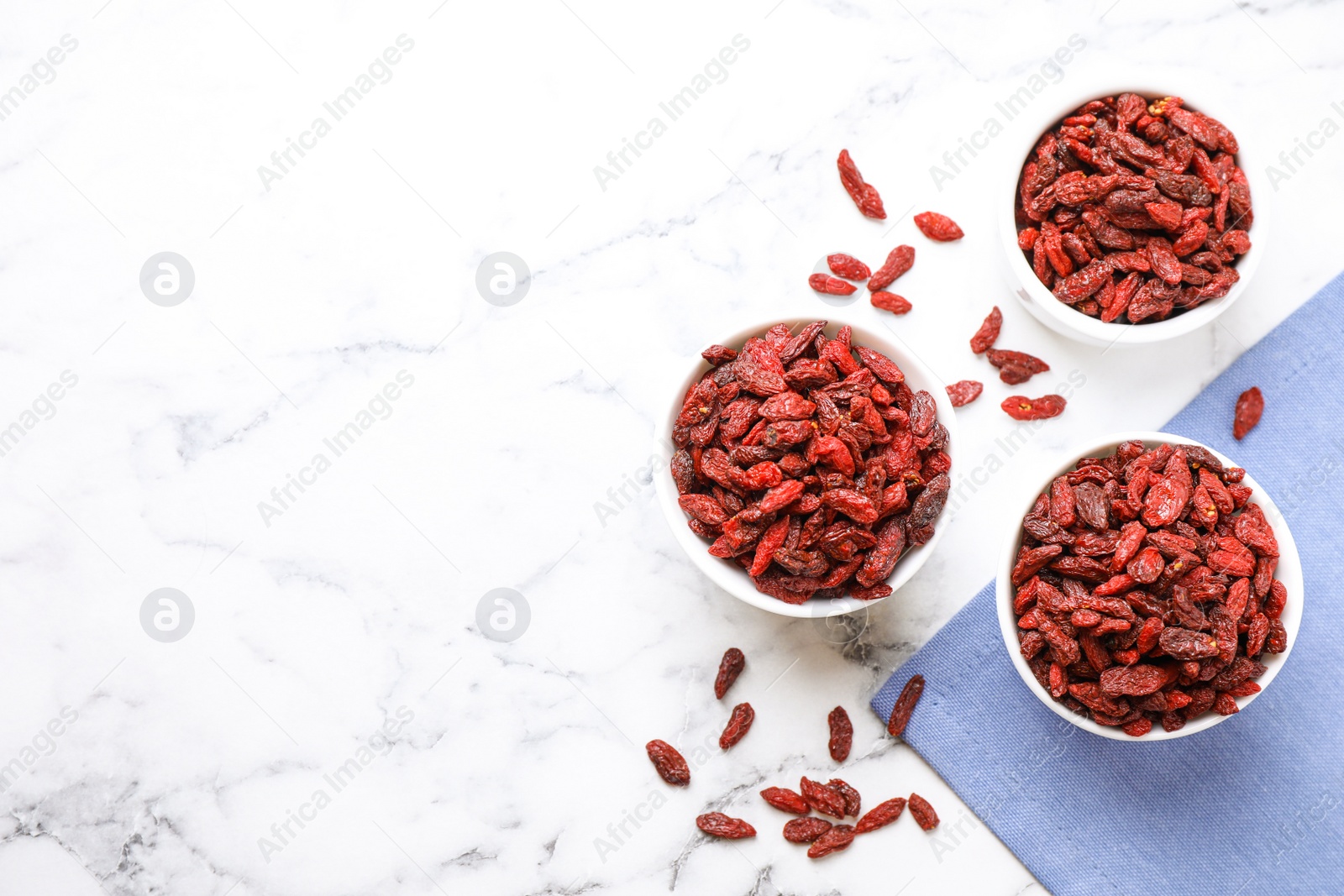 Photo of Dry goji berries on marble table, flat lay. Space for text