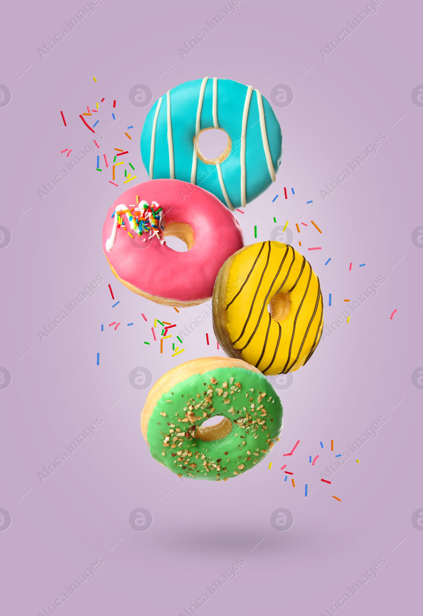 Image of Sweet tasty donuts with sprinkles falling on pale purple background