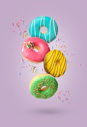 Image of Sweet tasty donuts with sprinkles falling on pale purple background