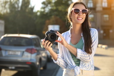 Photo of Young photographer with professional camera outdoors. Space for text