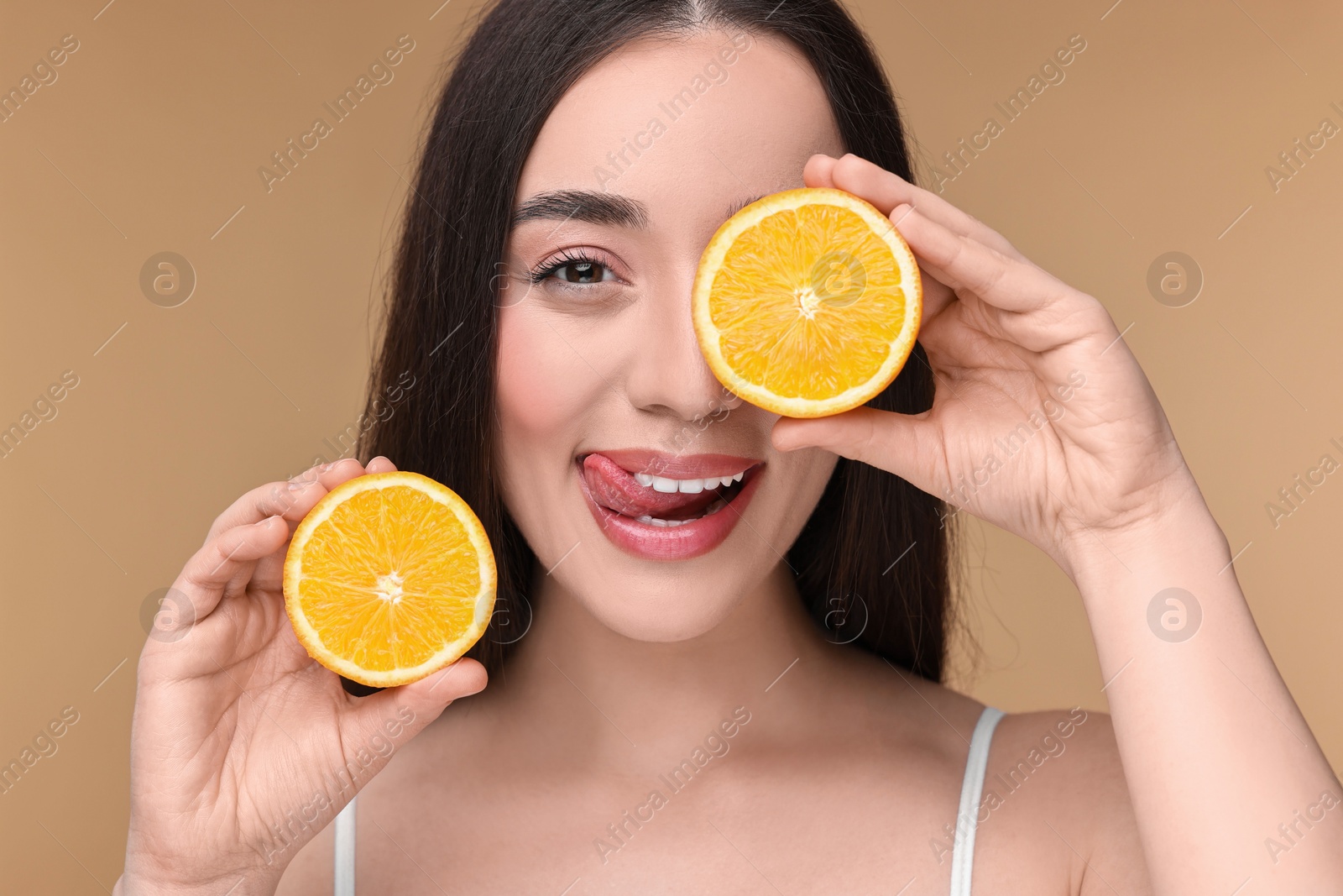 Photo of Beautiful young woman with pieces of orange on beige background