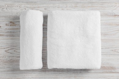 Photo of Soft folded and rolled towels on white wooden table, flat lay