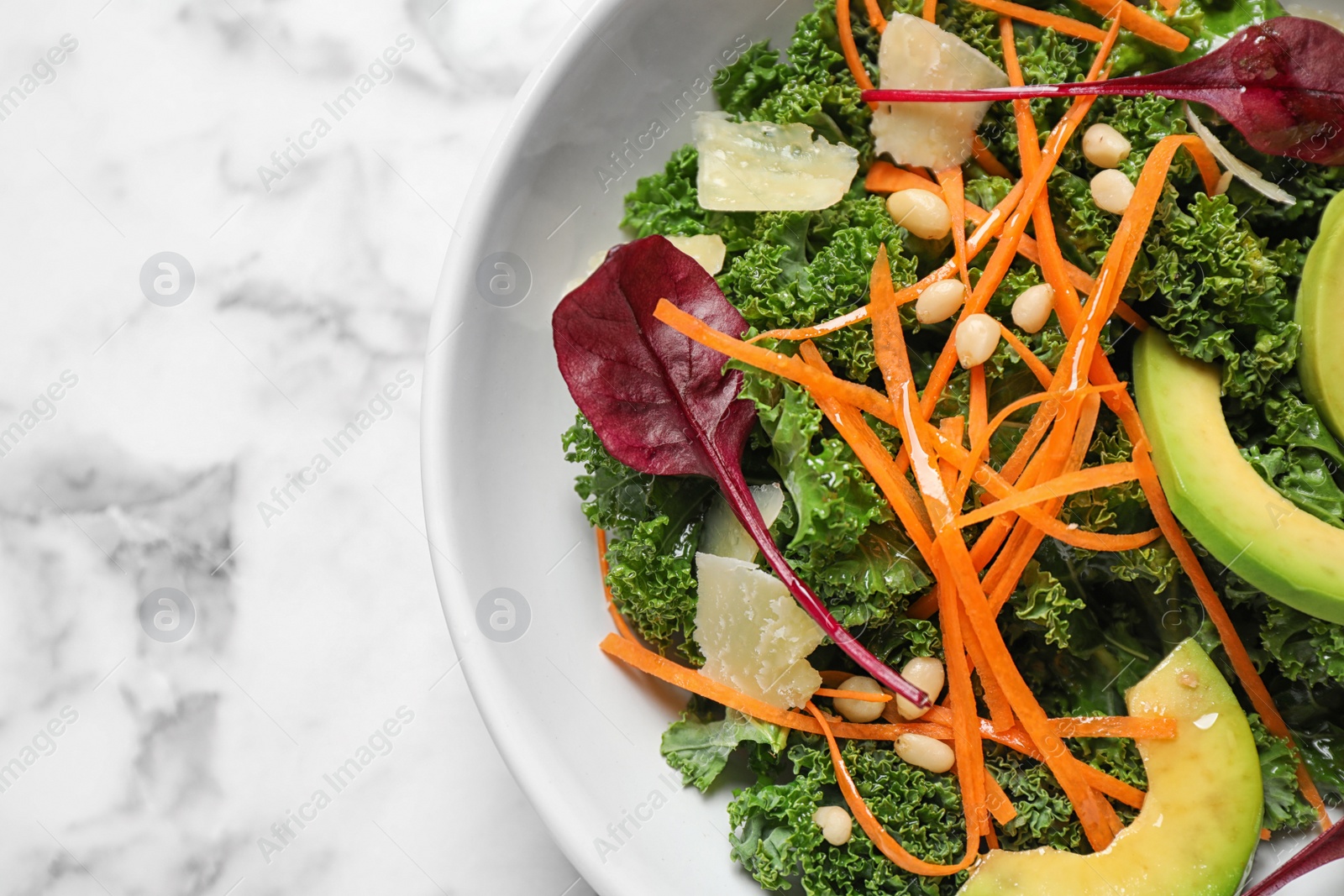 Photo of Tasty fresh kale salad on marble table, top view