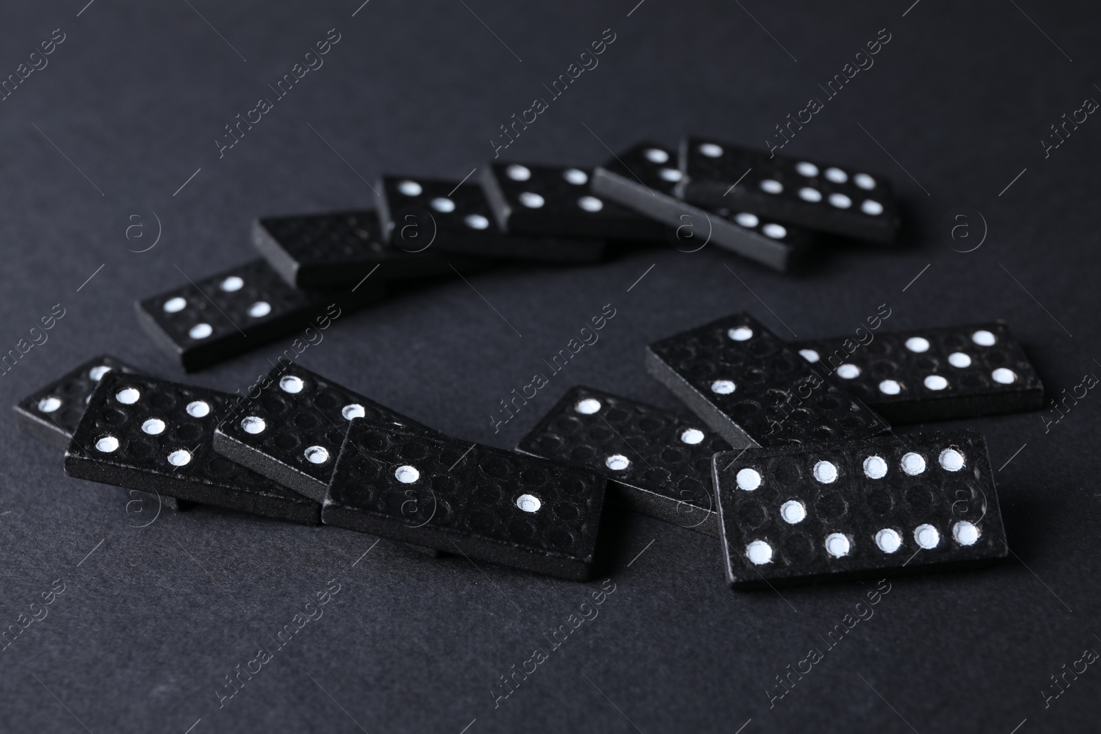 Photo of Many fallen domino tiles on black background