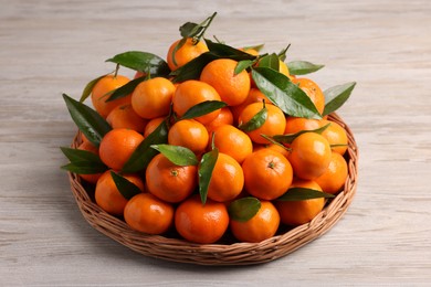 Fresh ripe juicy tangerines and green leaves on white wooden table