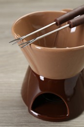 Photo of Fondue set on wooden table, closeup. Kitchen equipment