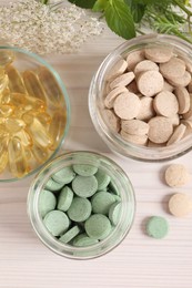 Photo of Different pills and herbs on white wooden table, flat lay. Dietary supplements