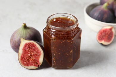 Photo of Jar of tasty sweet jam and fresh figs on white table, closeup