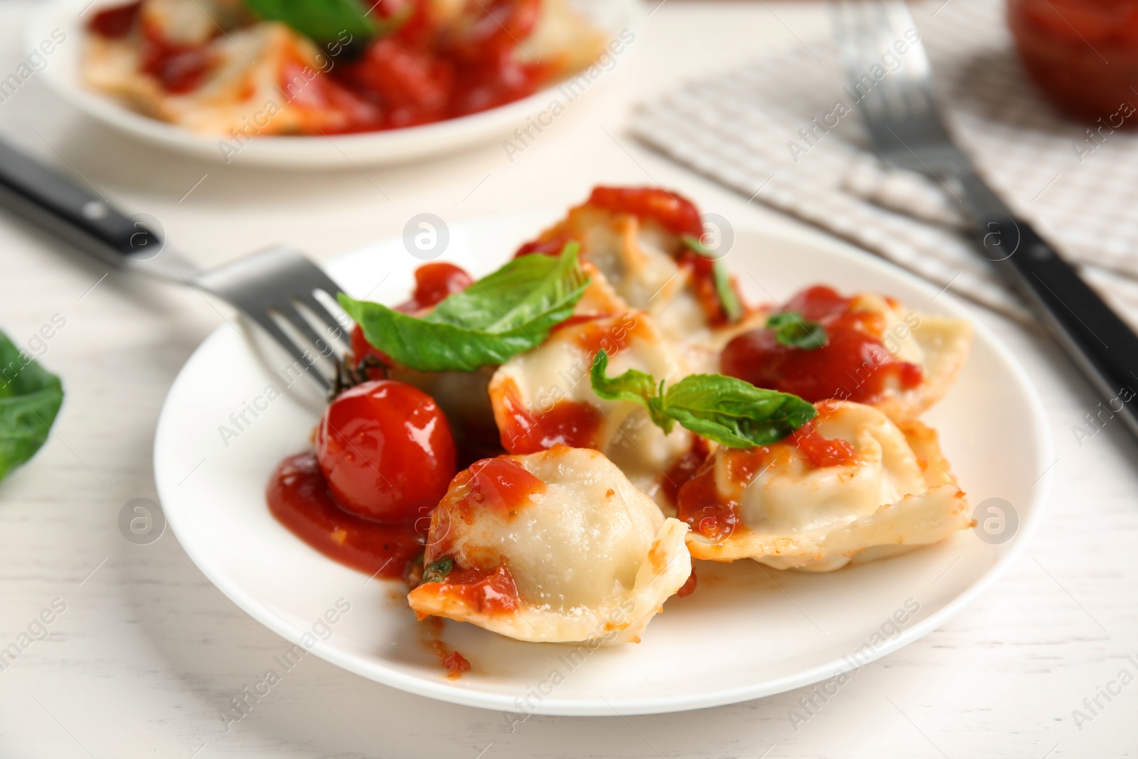 Photo of Tasty ravioli with tomato sauce served on white table