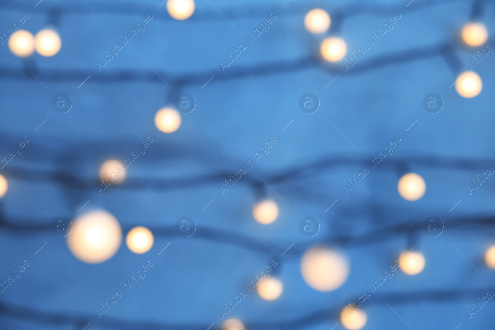 Photo of Blurred view of Christmas lights on color background