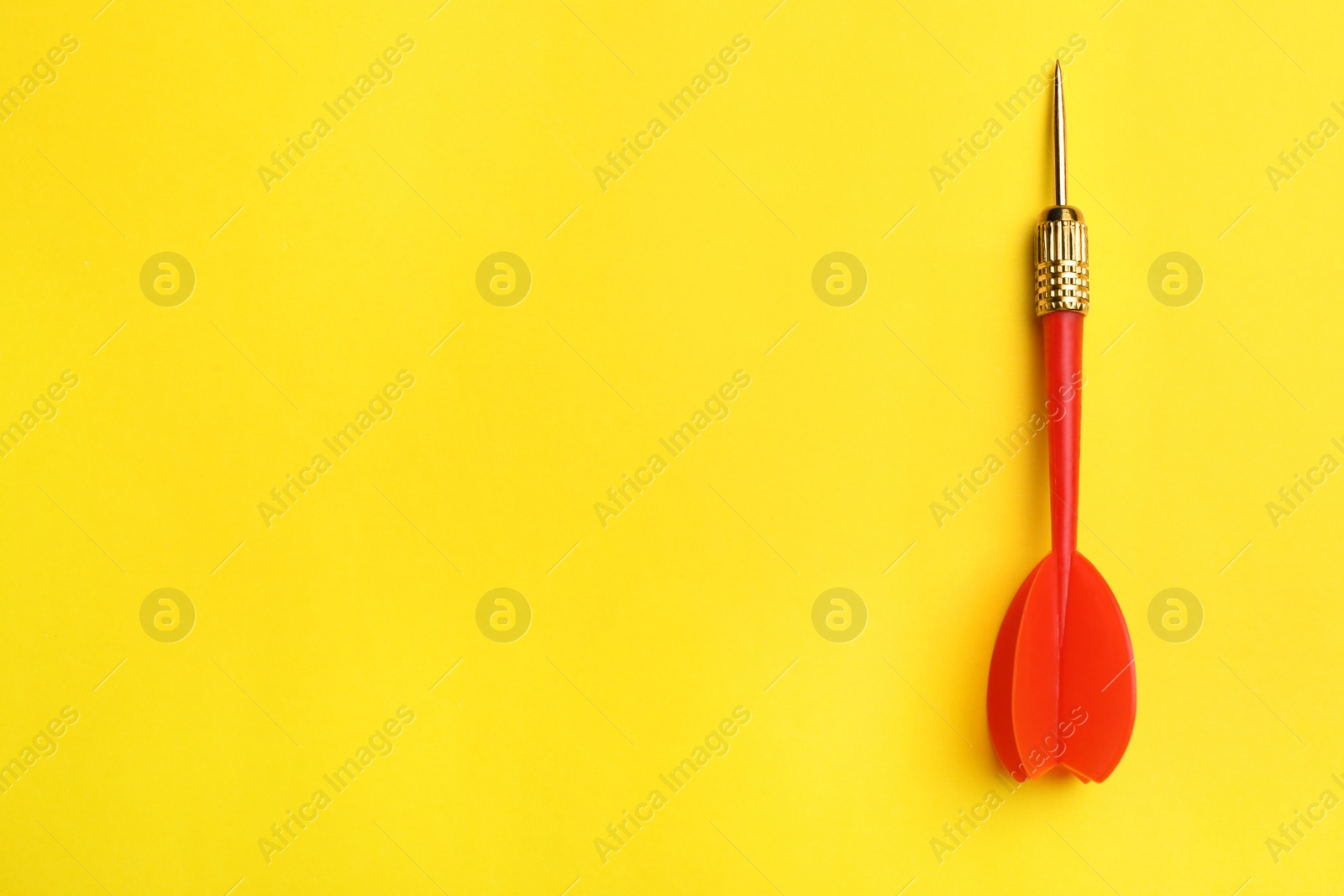 Photo of Red dart arrow on yellow background, top view with space for text