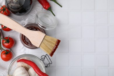 Marinade in jar, ingredients and basting brush on white tiled table, flat lay. Space for text