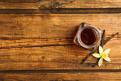 Photo of Homemade vanilla extract on wooden table, flat lay. Space for text