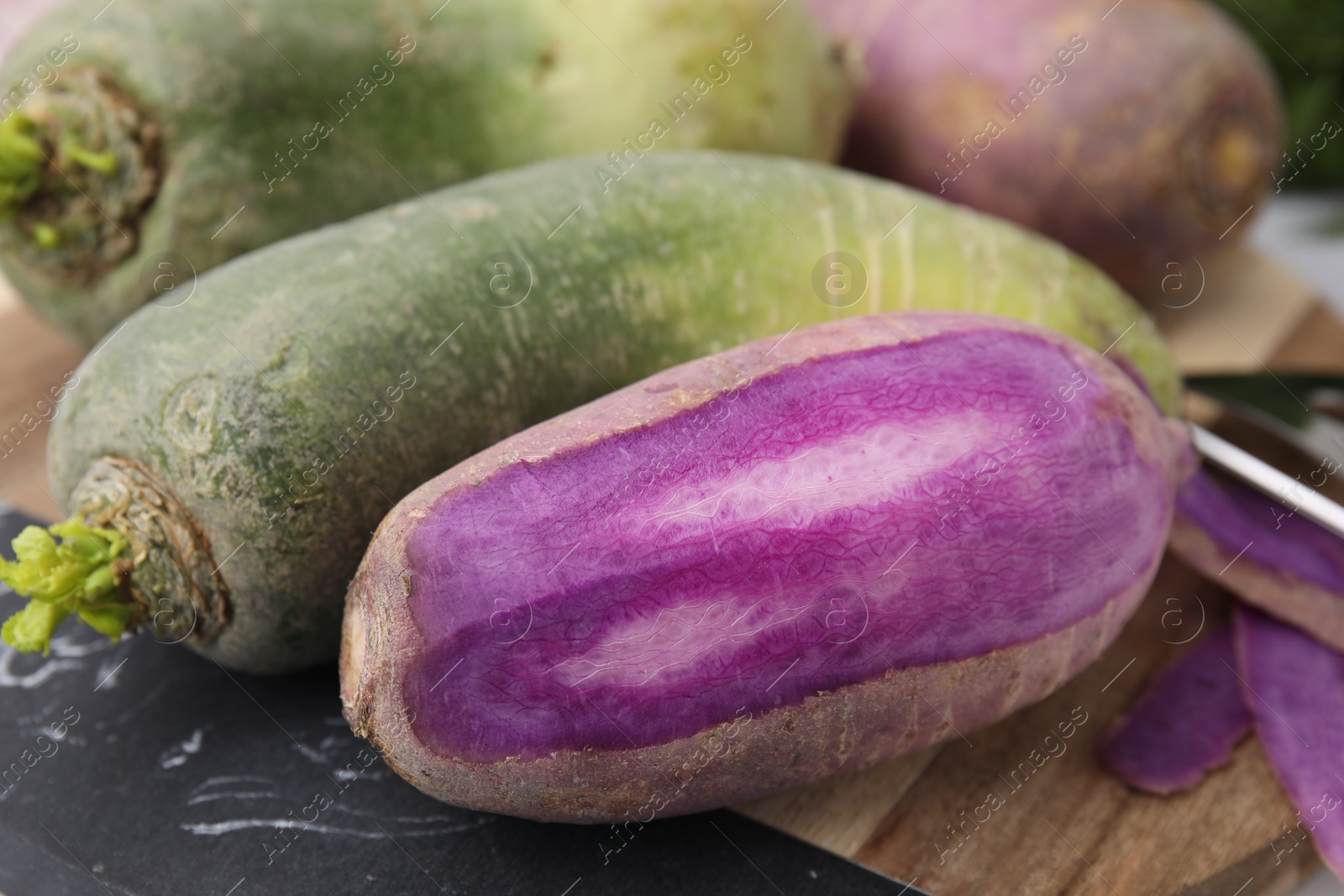 Photo of Purple and green daikon radishes on board, closeup