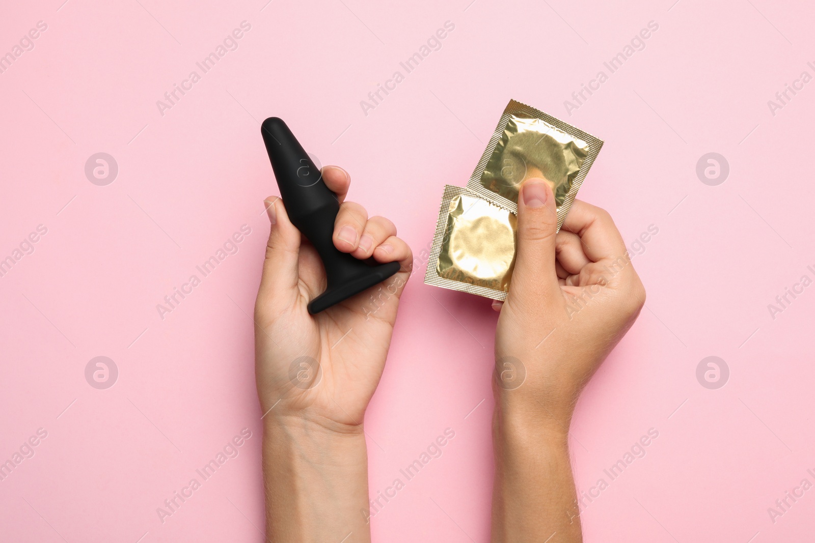 Photo of Woman with anal plug and condoms on pink background, top view. Sex game